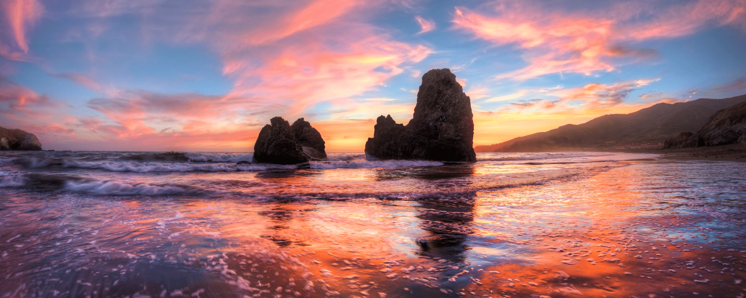 a beautiful sunset at the rodeo beach. rocky cliffs projecting above the beach water