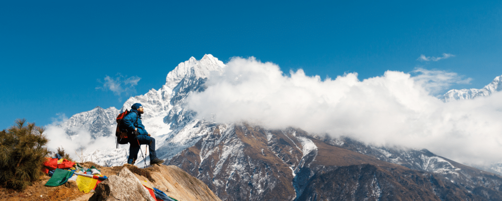 a man with backpack standing on top of a mountain during churdhar trek