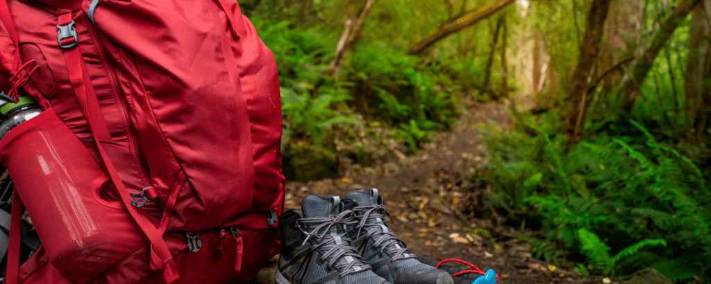 a red backpack adn black shoes on a trekking trail