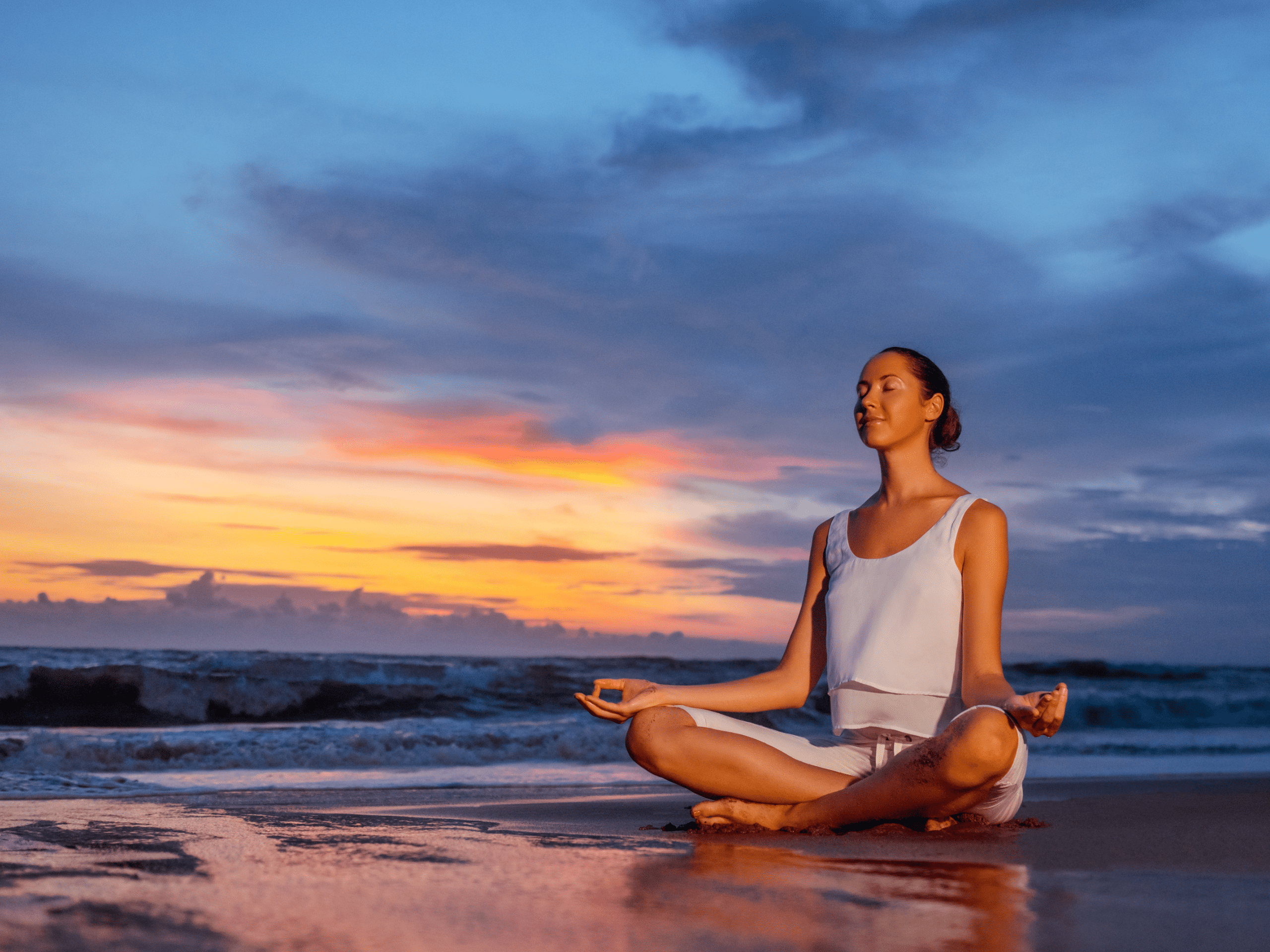 a woman meditating and relaxing at the beach