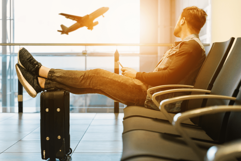 a man sitting at the airport watching a flight take off