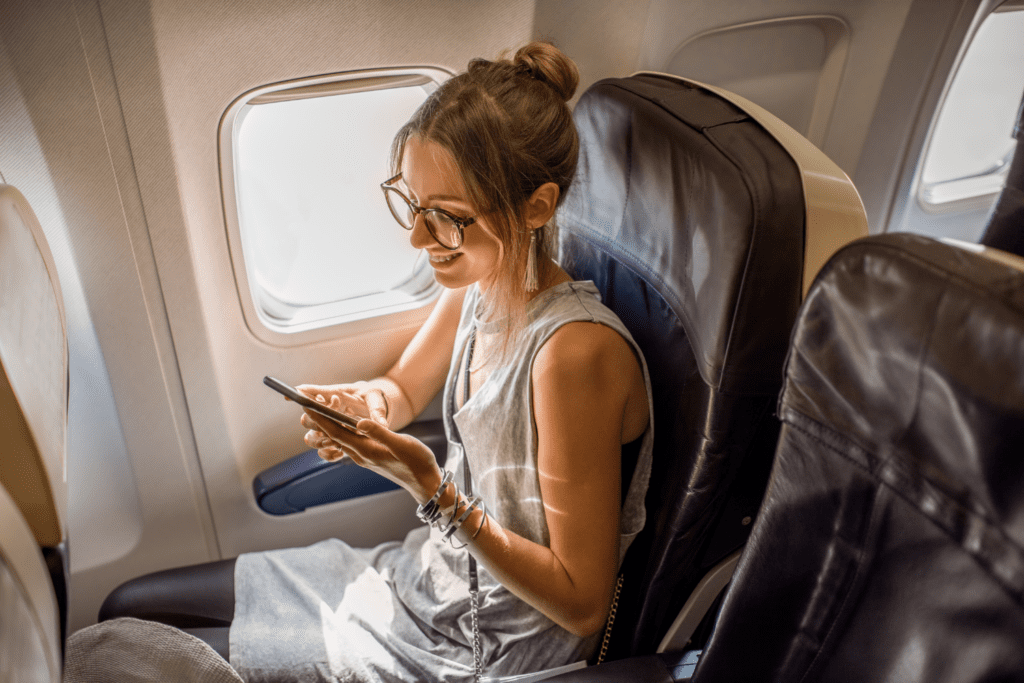 a woman sitting with her phone on a comfortable seat inside spirit airlines