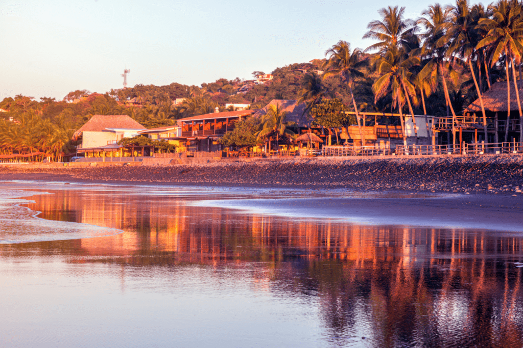 beautiful beach, palm trees and small houses on the playa el tunco beach in libertad el salvador.