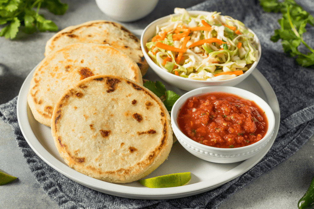 Pupusas, a local cuisine of Libertad El Salvador. Served on a plate along with vegetable salad and tomato sauce.